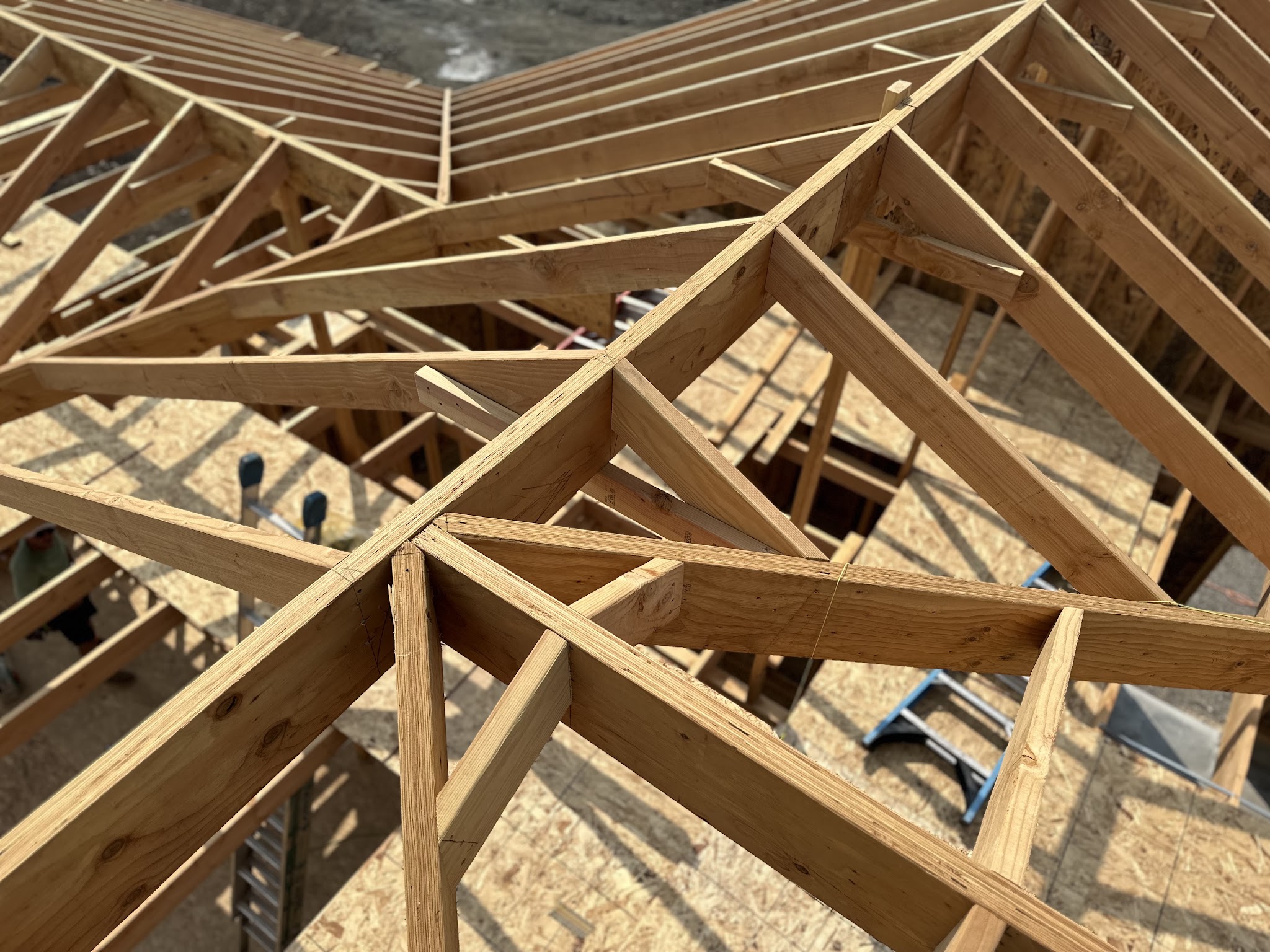 Roof truss framing on a new build by Spence Construction, crew member visible working the ridge