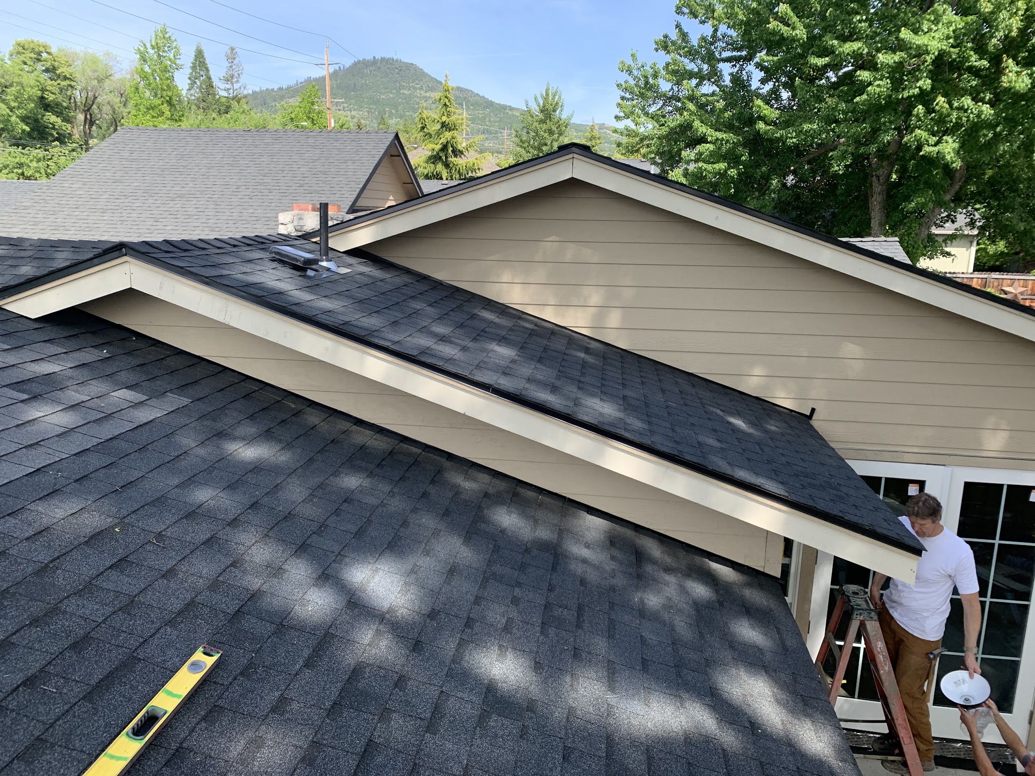 Finish roof and gutter work on a completed home with a mountain in the background