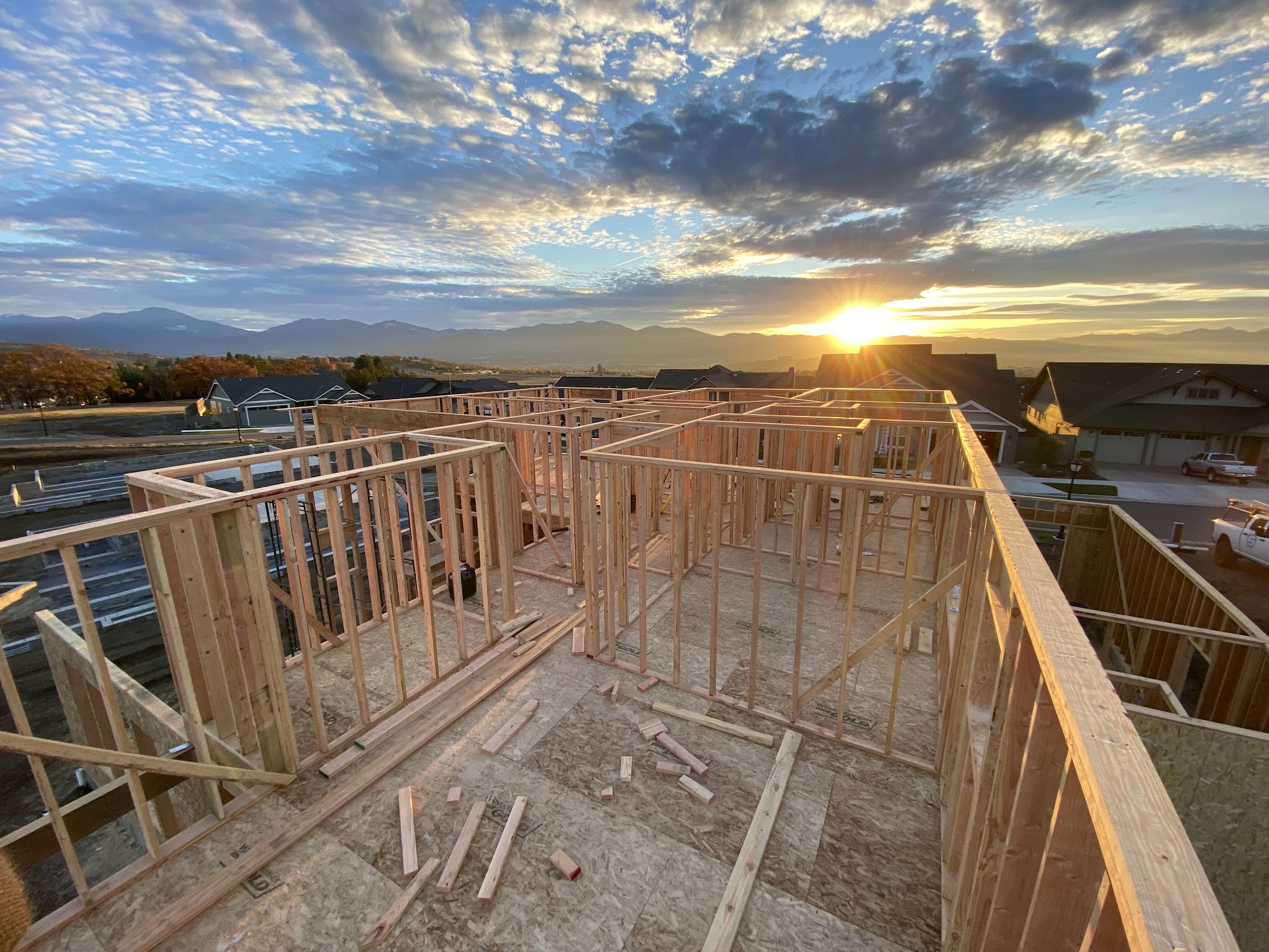 Sunrise over roof framing on a Spence Construction job site, mountains in the distance